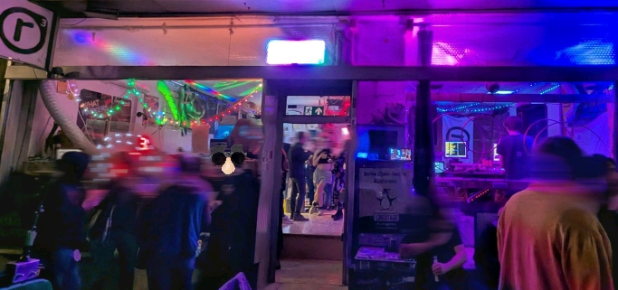 a photo from outside of realraum during the last party. colourful lights, great atmosphere, many people drinking and talking